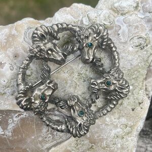 Vintage Aries rams’ heads brooch in silver tone. Blue rhinestone eyes.